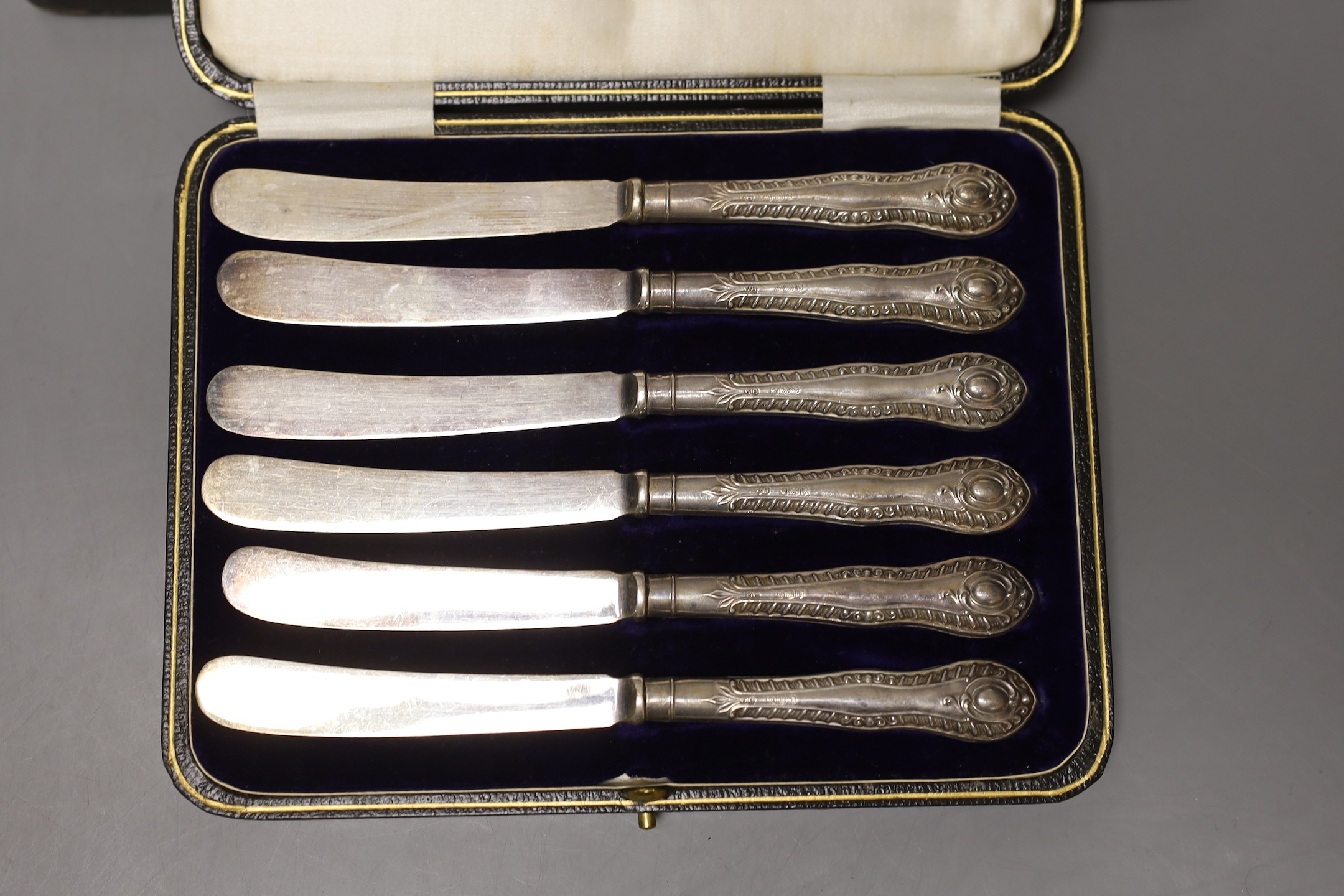 A cased set of twelve Edwardian silver teaspoons with tongs, a cased set of six tea knives and a cased set of 5 (ex 6) silver teaspoons.